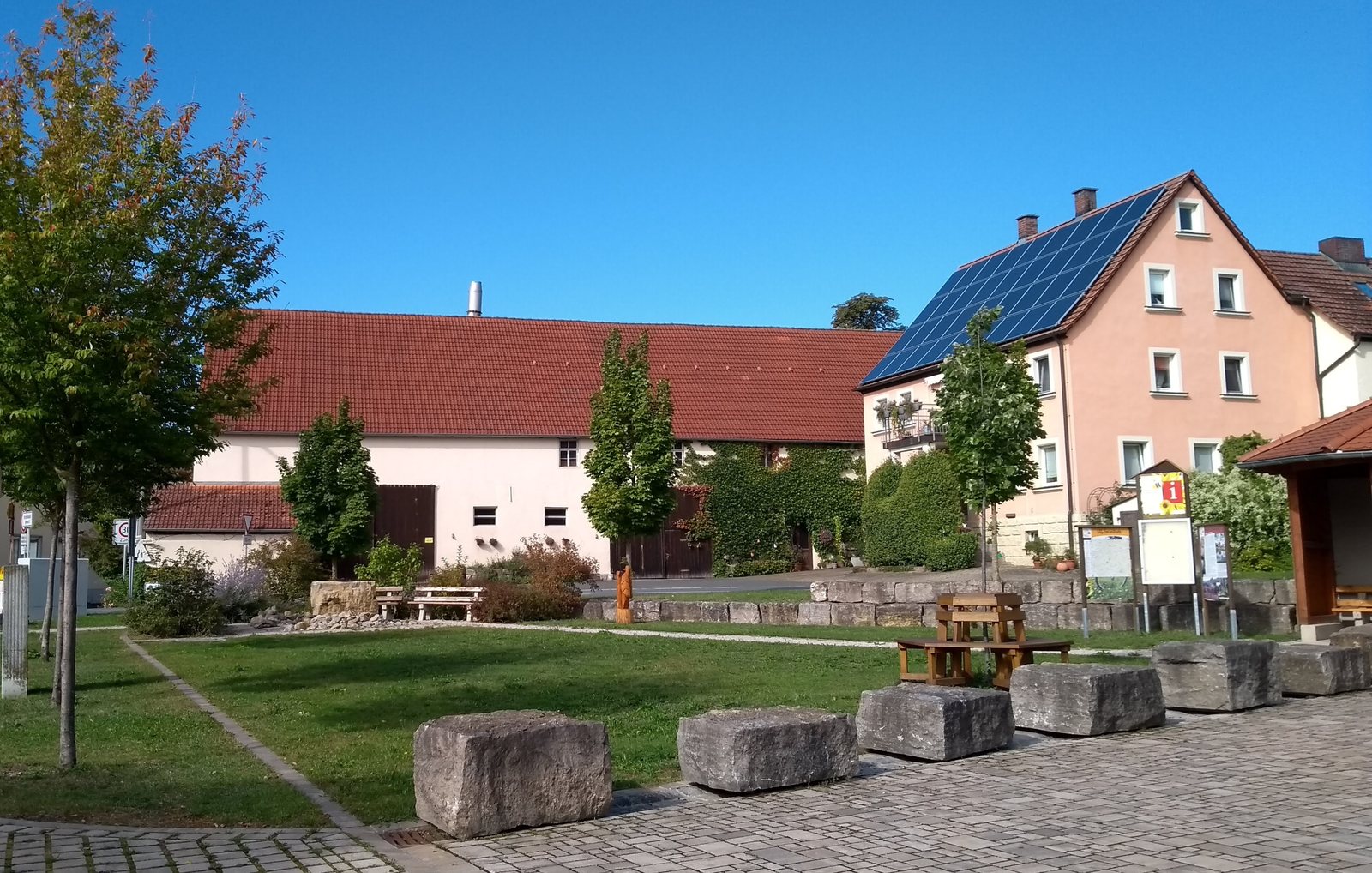 Dorfplatz in Markt Taschendorf mit Sitzsteinen, Bänken und Infotafel